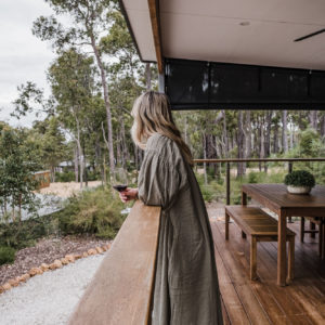 Woman drinking wine on balcony looking out to garden
