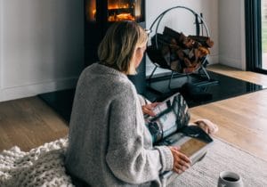 a woman reading a in front of a woodfire