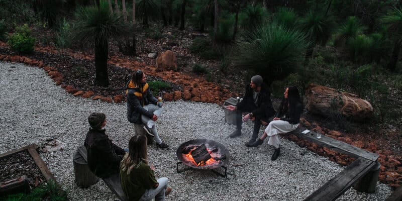 people enjoy wine and beer beside an outdoor fire pit